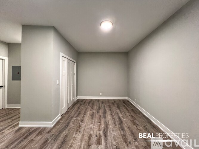 A spacious room with wood flooring and white walls.