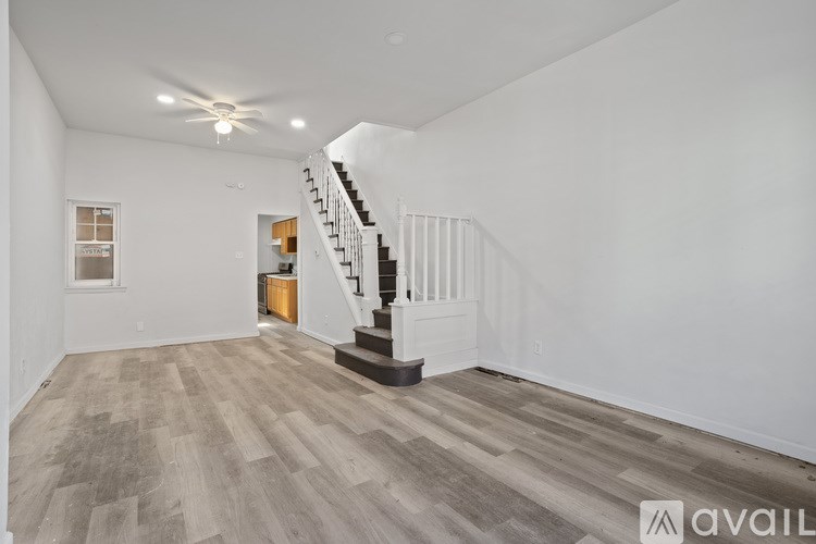 A spacious room with a staircase and wooden flooring.