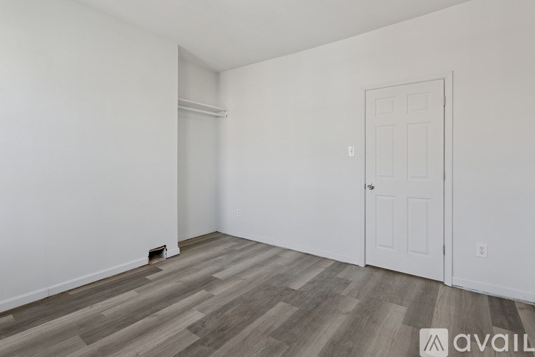 A room with a white door and a wooden floor.