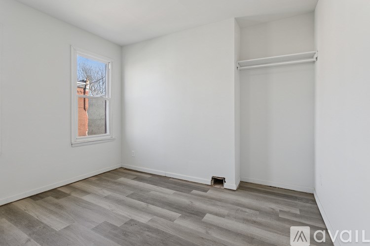 A room with a window and a wooden floor.