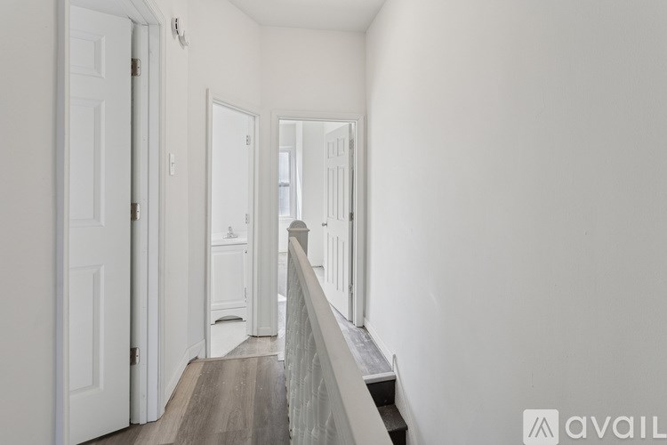 A hallway with white doors and a wooden floor.
