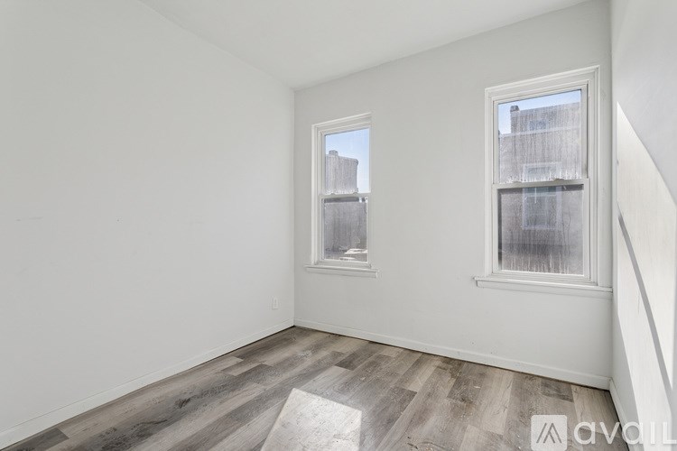 A room with two windows and wooden flooring.