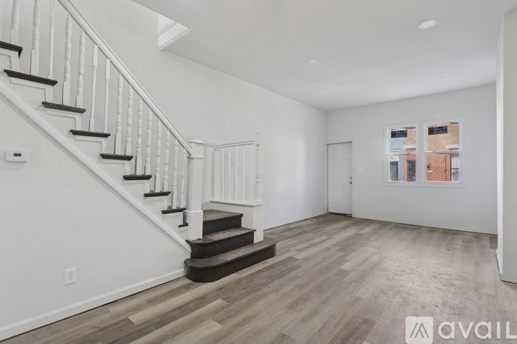 A spacious room with a staircase and a window showing a cityscape.