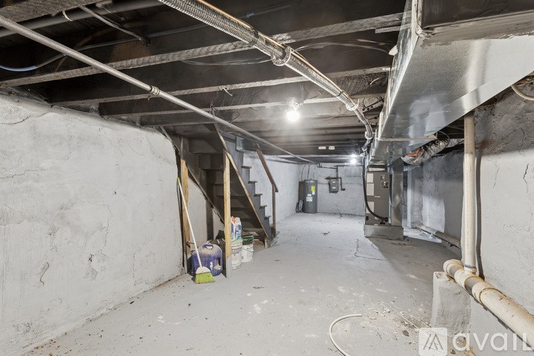 A long hallway with a pipe on the wall and a broom leaning against it.