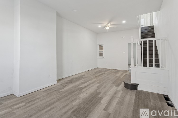 A spacious room with wooden flooring and a staircase.