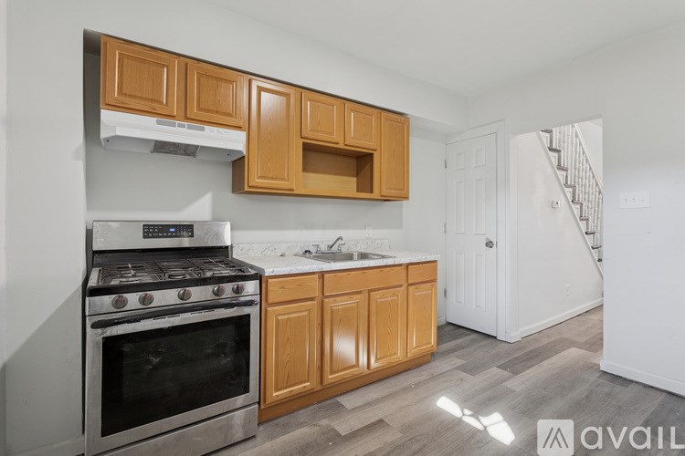 A kitchen with a stove, cabinets, and a sink.
