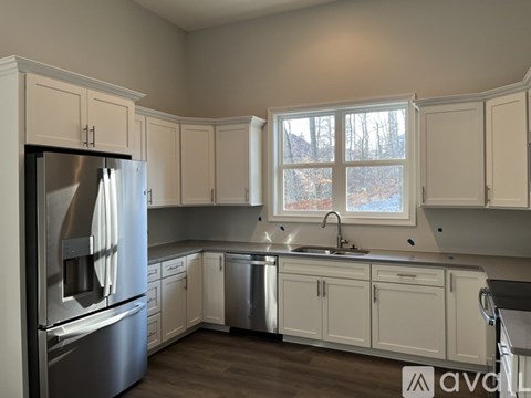 A kitchen with white cabinets and a stainless steel refrigerator.
