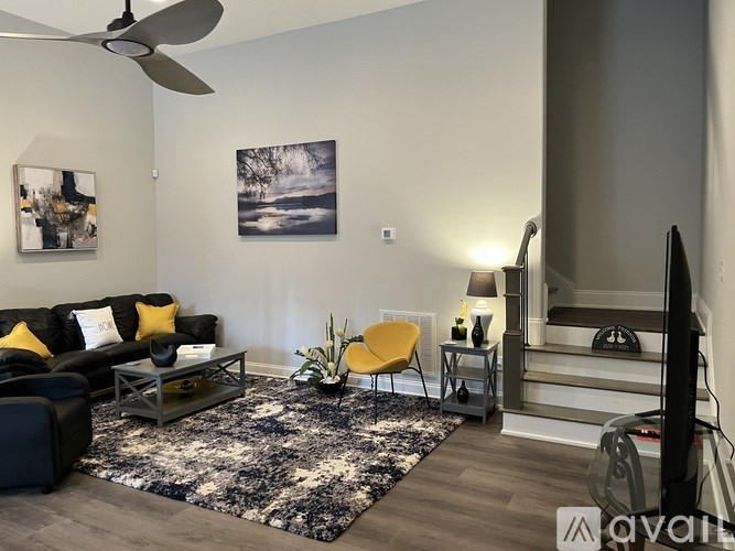 A living room with a black couch, yellow chair, and a rug.