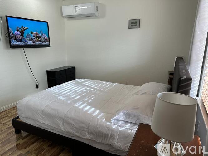 A bedroom with a bed, a television, and a lamp.