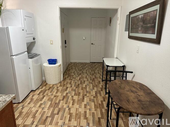 A kitchen area with a refrigerator, a table, and chairs.