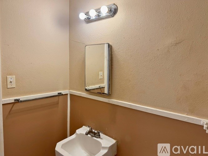 A bathroom with a sink, mirror, and light fixture.