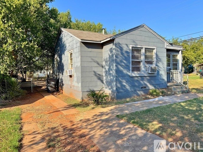 A small grey house with a brown roof and a white door.