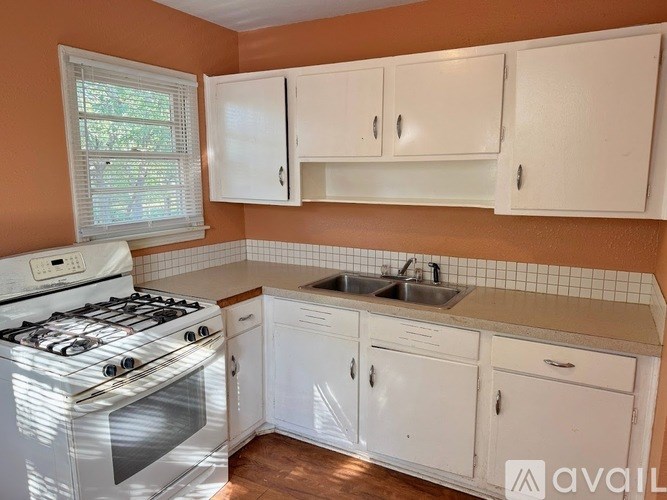 A kitchen with a white stove and cabinets.