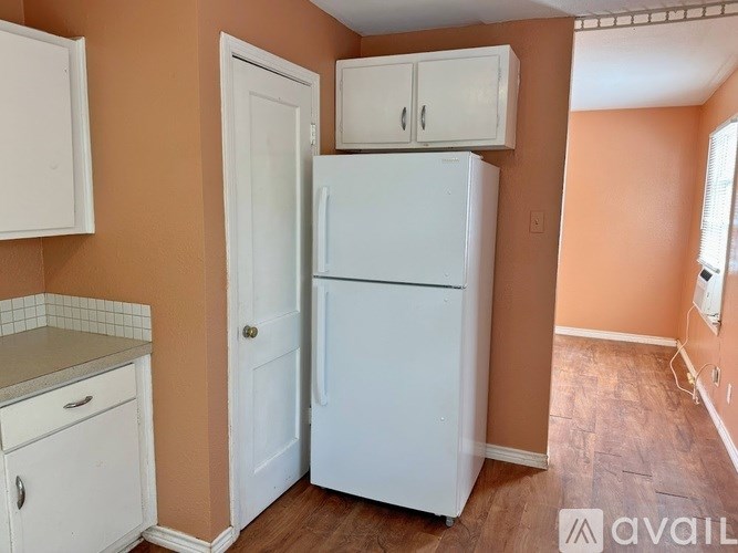 A white refrigerator in a kitchen with orange walls.