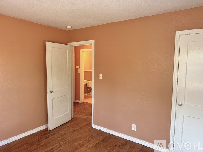 A room with brown walls and wooden floors, with two white doors.
