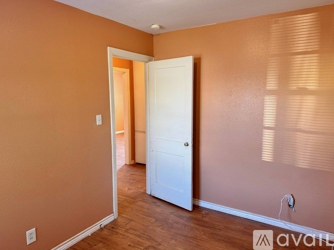 A room with a white door and wooden floor.