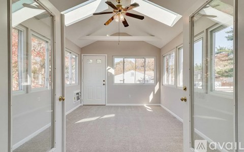 A sunny day in a white room with a ceiling fan.