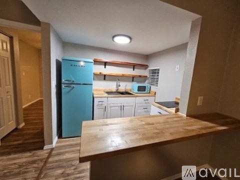 A kitchen with a blue refrigerator and white cabinets.