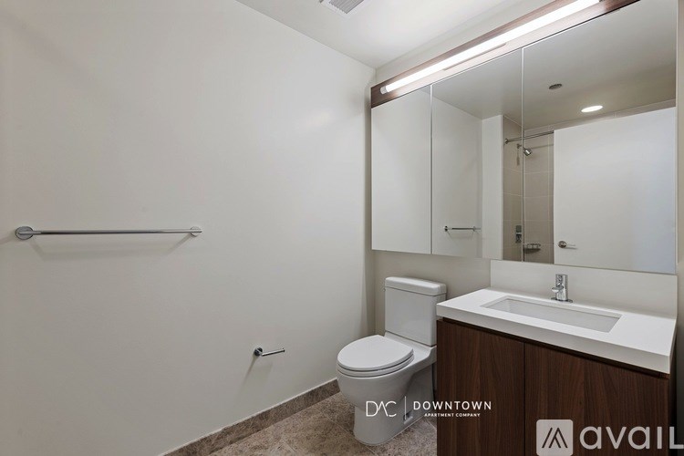 A bathroom with a toilet, sink, mirror and a towel rack.