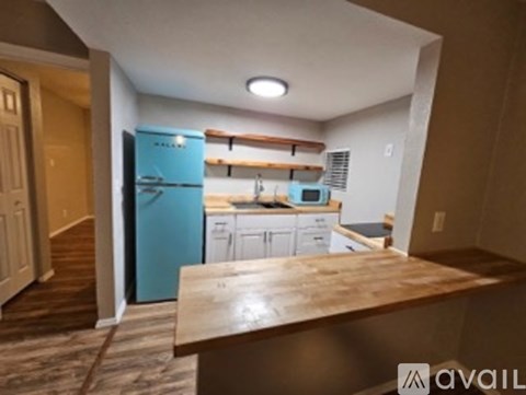 A kitchen with a blue refrigerator and white cabinets.