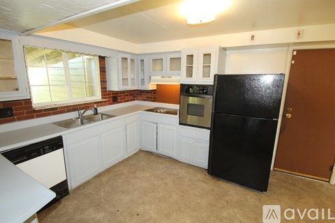 A kitchen with white cabinets and a black refrigerator.