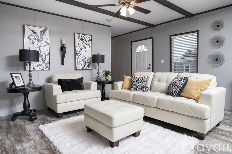 A living room with a white couch, a black table, and a white rug.