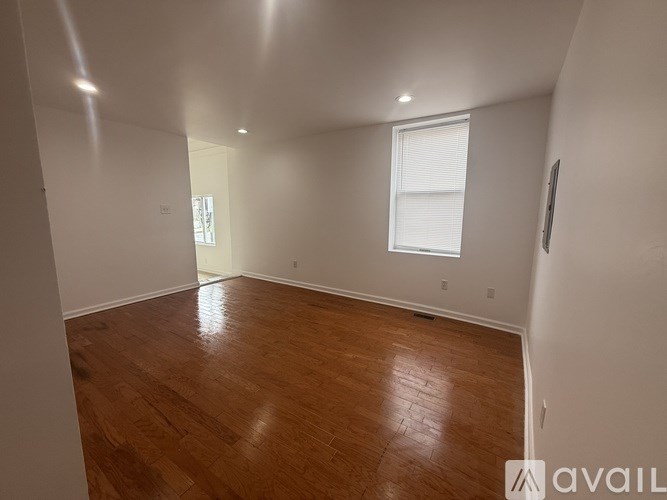 A room with wooden flooring and a window with blinds.
