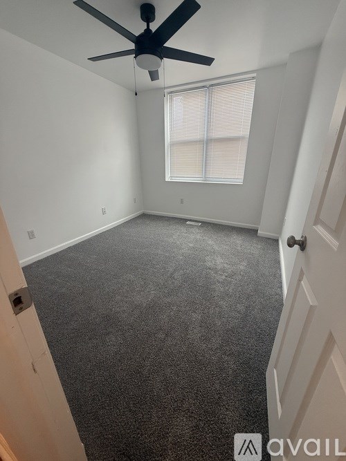 A room with a ceiling fan and carpeted floor.