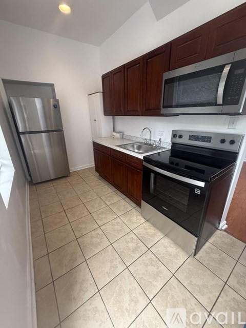 A kitchen with a stainless steel refrigerator, microwave, oven, and sink.