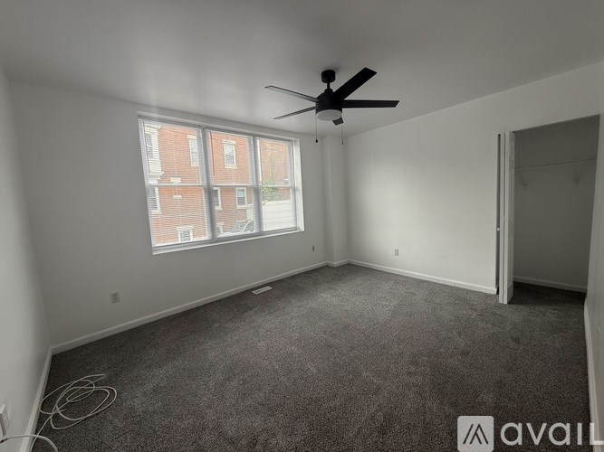 A room with a ceiling fan and a window overlooking a brick building.