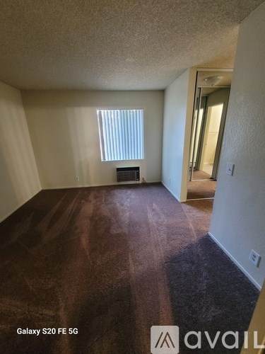 A room with a wooden floor and a window with blinds.