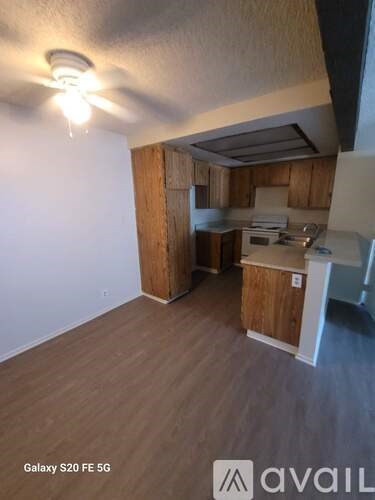 A kitchen area with wooden cabinets and a ceiling fan.