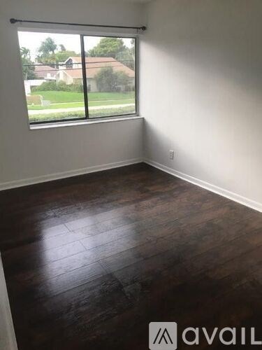 A room with a large window and wooden flooring.