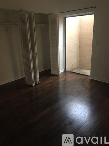 A room with a dark wood floor and white walls.