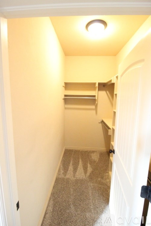 A hallway with a carpeted floor and a light on the ceiling.