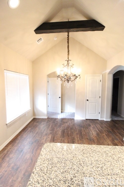 A room with a chandelier and a rug on the floor.