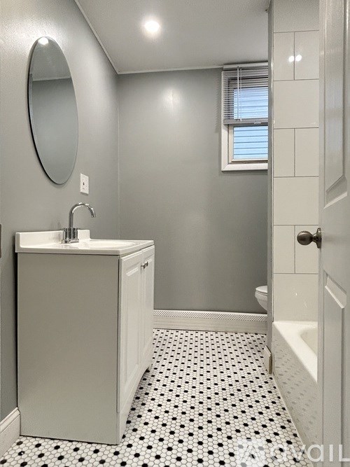 A bathroom with a sink, mirror, and tiled floor.