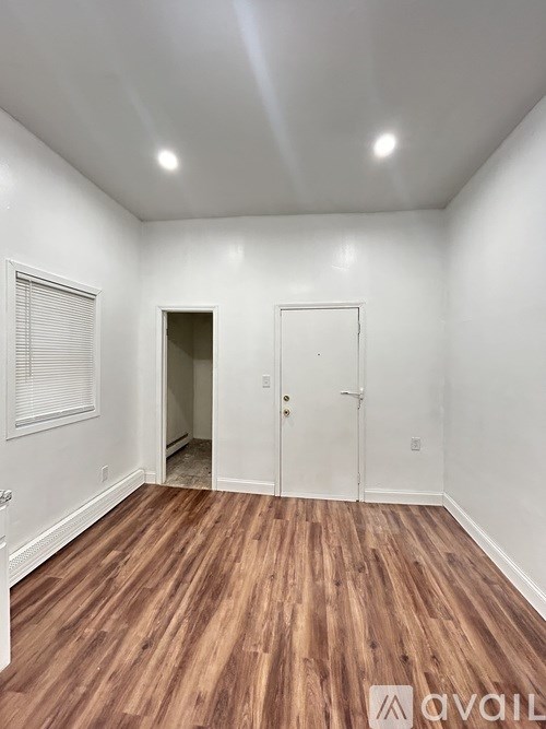 A room with wooden flooring and white walls.