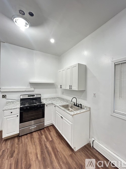 A kitchen with white cabinets and a wooden floor.