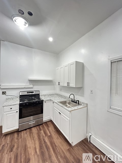 A kitchen with white cabinets and a wooden floor.