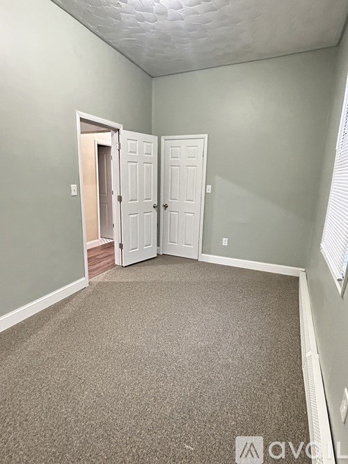 A room with grey walls and a carpeted floor with two white doors.