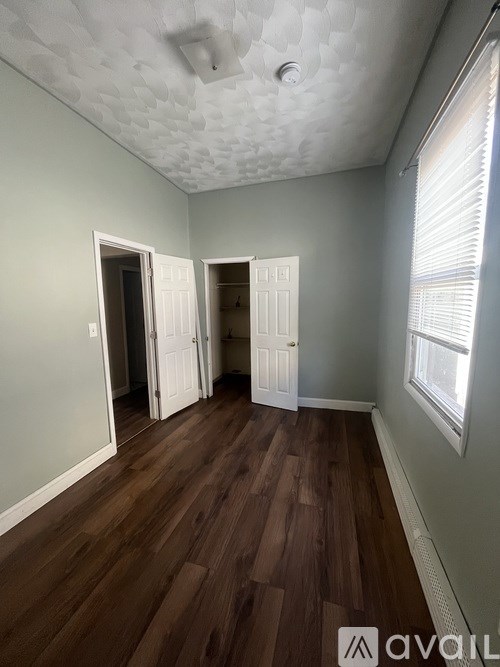 A bedroom with a white bed and a painting of a woman on the wall.