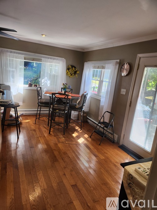 A dining room with a wooden floor and a table set for four.