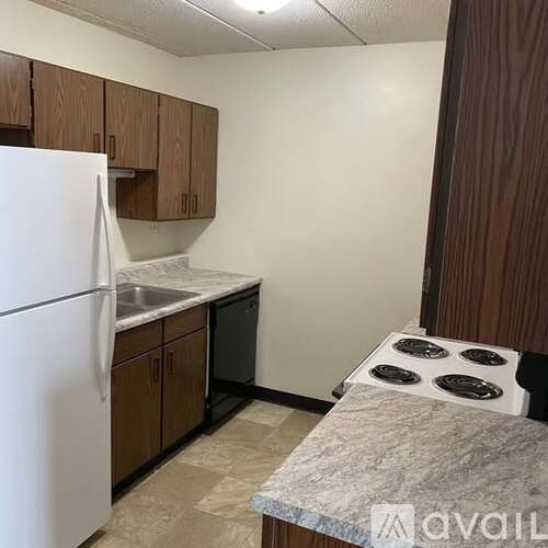A kitchen with a white refrigerator, brown cabinets, and a marble countertop.