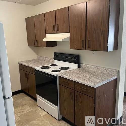 A kitchen with a white stove top oven and brown cabinets.