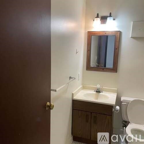 A bathroom with a toilet, sink, and mirror.