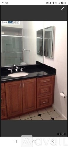 A bathroom with a sink, mirror, and wooden cabinets.