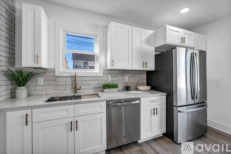 A kitchen with white cabinets and a black refrigerator.
