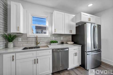 A kitchen with white cabinets and a black refrigerator.