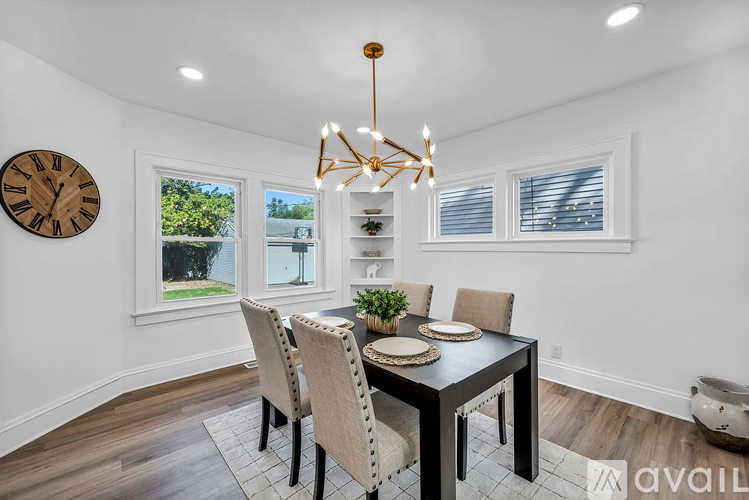 A dining room with a table set for four and a chandelier hanging from the ceiling.